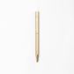 Der ENTREPÔT - YSTUDIO Klassischer Revolve Kugelschreiber Schlank mit einem goldenen sechseckigen Messingkörper steht senkrecht vor einem schlichten weißen Hintergrund.