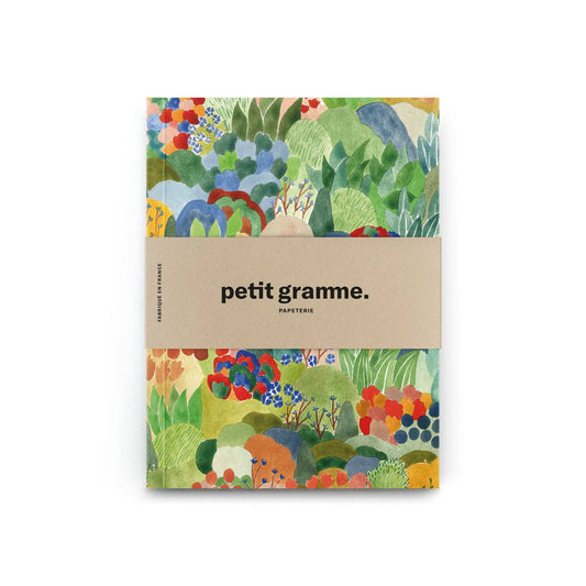 Das Petit Gramme - Luxuriance Notizbuch im Taschenformat zeigt ein abstraktes, buntes Blumencover mit beiger Banderole und mittlerem "PAPETERIE"-Schriftzug. Es besteht aus recycelten Fasern und Papier aus nachhaltiger Forstwirtschaft.