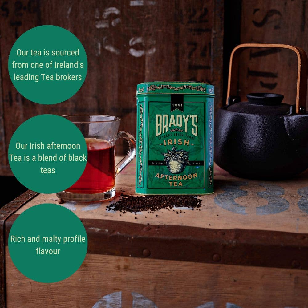 Eine grüne Dose Brady's Coffee Company – Bradys irischer Nachmittagstee steht auf einer rustikalen Holzoberfläche neben einer schwarzen Teekanne und einer Glastasse, wobei verstreute Teeblätter und grüne Kreise den irischen Geschmack hervorheben.