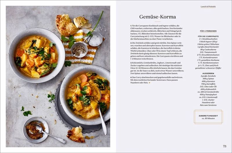 Auf einer grauen Fläche sind zwei Schalen mit Gemüse-Korma mit Naan abgebildet, die von der britischen Küche inspiriert sind. Auf der rechten Seite befindet sich eine Rezeptanleitung aus "London Lovestory" vom Hölker Verlag. Die eine Schale steht auf einem weißen Teller mit Samen, die andere neben einer gestreiften Serviette.