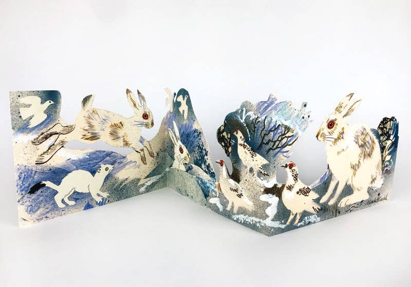 Die Art Angels - Winter-Wildtier-Collage-Karte von Mark Hearld zeigt illustrierte Wintertiere wie Hasen und Schneehühner in einer verschneiten blau-weißen Szene, inspiriert von seiner Winter Wildlife Collage.