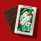 Ein Bio-Schokoladenriegel von I AM ITALIANO - Parenti mit Milch und Kaffee liegt neben einer Box mit Schneemann- und Winterkind-Illustration, beschriftet mit "I AM ITALIANO" und "THE MOST ITALIAN CHOCOLATE".