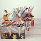 Scherenschnitte von Ballerinas in bunten Kostümen stehen auf einer hellen Holzoberfläche. Die Tänzer Ausstanzkarte von Sarah Young für Art Angels zeigt florale und abstrakte Muster und ist ein charmantes Design-Geschenk für jeden Anlass.