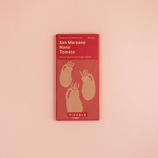 Eine rote Piccolo Seeds-Packung mit der Aufschrift „Tomate San Marzano nano“ zeigt eine goldene Tomatenillustration, ideal zum Anbauen oder für die Zubereitung von Pelati. Die Marke „Piccolo Seeds“ steht unten, und die Packung ist auf hellrosa Hintergrund abgebildet.