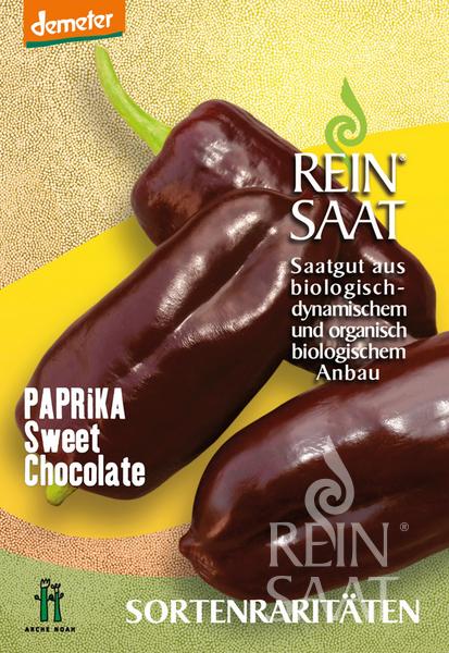 Samenpaket für ReinSaat - Paprika 'Sweet Chocolate' von Reinsaat, mit drei dunkelrotbraunen Paprikaschoten auf gelb-goldenem Hintergrund mit deutschem Text zum biologischen Anbau im Gewächshaus.