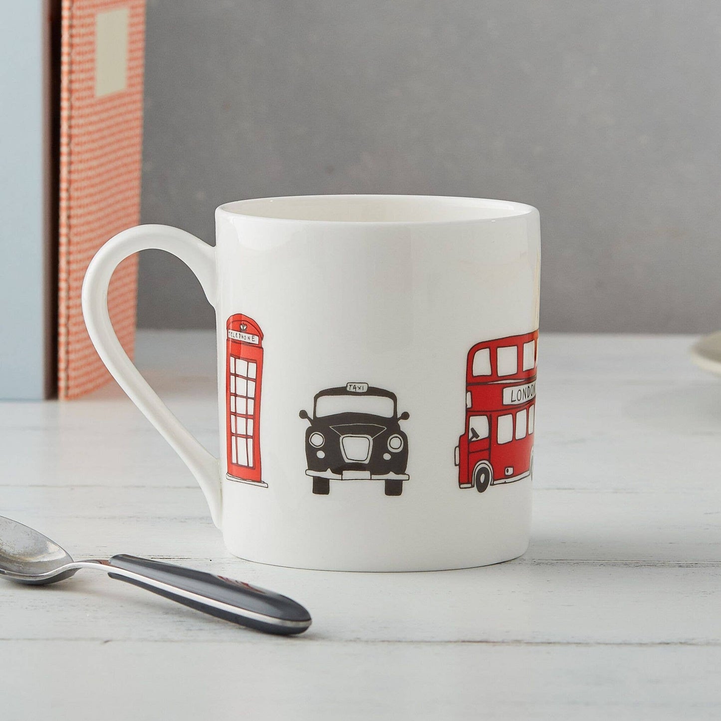 Der Victoria Eggs - London Skyline Becher von Victoria Eggs ist ein Becher aus feinem Knochenporzellan mit Abbildungen einer roten britischen Telefonzelle, eines schwarzen Taxis und eines roten Doppeldeckerbusses – ein bezauberndes britisches Souvenir für jeden Fan.