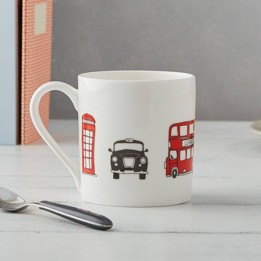 Der Victoria Eggs - London Skyline Becher von Victoria Eggs ist ein Becher aus feinem Knochenporzellan mit Abbildungen einer roten britischen Telefonzelle, eines schwarzen Taxis und eines roten Doppeldeckerbusses – ein bezauberndes britisches Souvenir für jeden Fan.