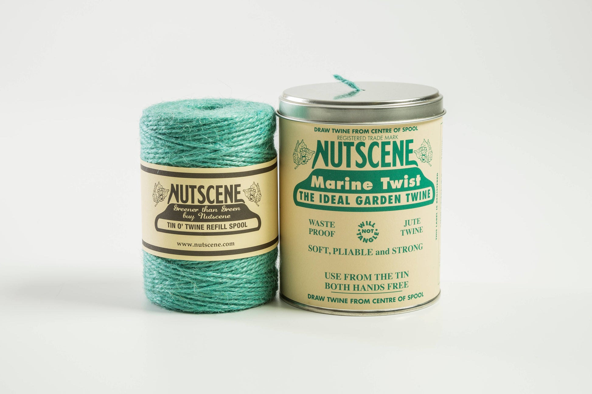 Eine Spule Nutscene-Gartenschnur steht neben der legendären Schnur in einer Dose (490 Fuß) von Nutscene Twines Ltd., beide mit der Aufschrift „Marine Twist – Die ideale Gartenschnur“. Aus dem Deckel der Dose kommt die dreilagige Juteschnur.
