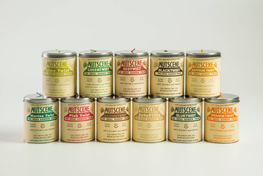 Zehn Dosen Nutscene Twines Ltd - Iconic Tin of Nutscene Twine (490 Fuß) werden in zwei Reihen auf weißem Hintergrund präsentiert. Jede Dose trägt ein einzigartiges Etikett und eine einzigartige Farbe, darunter Lime Twist, Green Twist und Red Twist 3-lagiges Jutegarn.