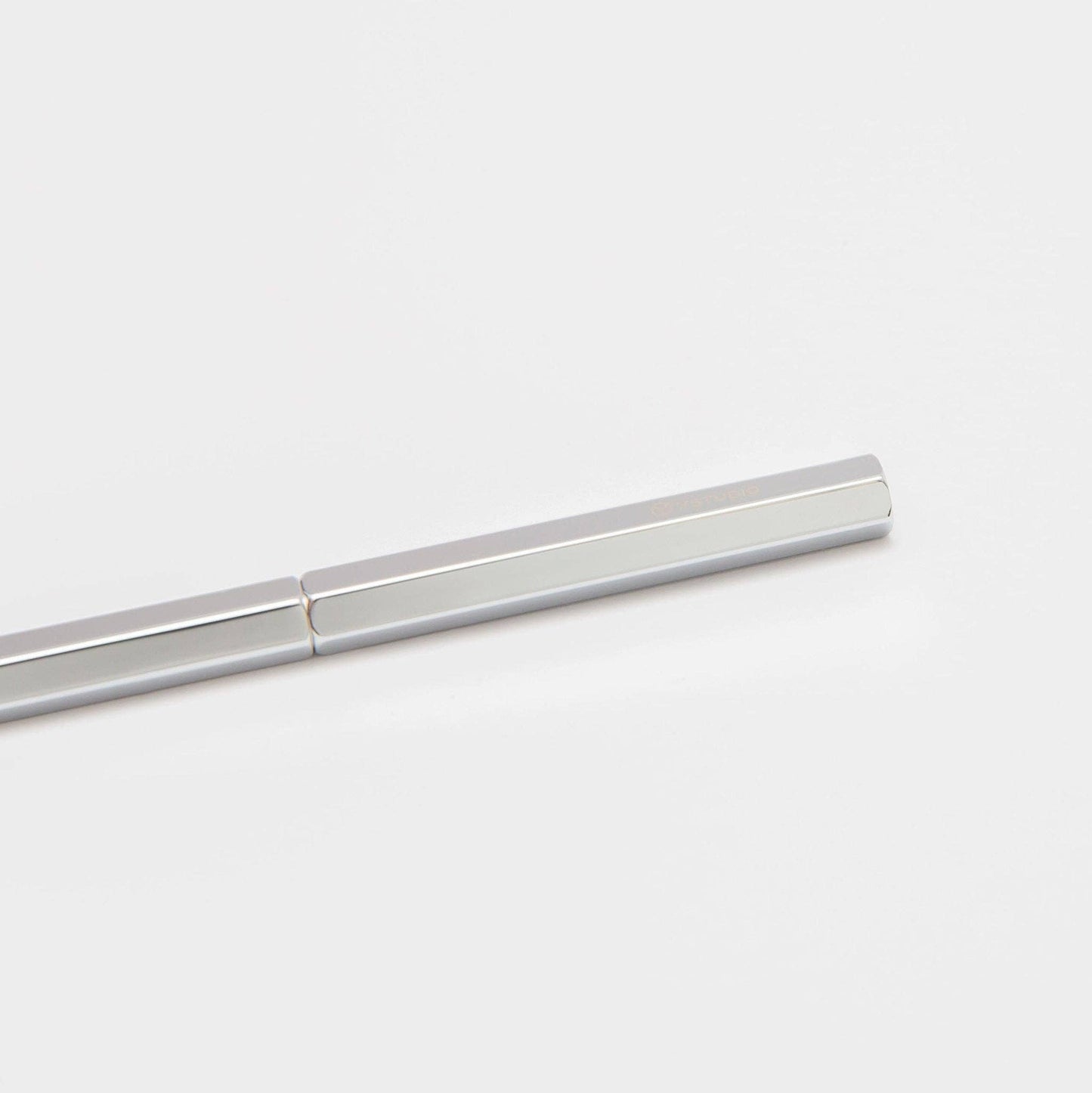 Der ENTREPÔT - YSTUDIO Klassischer Revolve Kugelschreiber Slim (Glänzendes Silber) liegt diagonal auf einem weißen Hintergrund und zeigt einen Teil des luxuriösen Schreibgeräts und dessen glänzendes Silber.