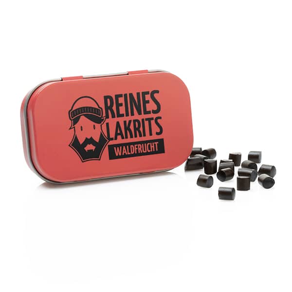 Eine rote LASSE LAKRITS-Metalldose mit der Aufschrift "Dose Reines Lakritz Waldfrucht" zeigt einen bärtigen Mann mit mehreren kleinen, schwarzen zuckerfreien Lakritzbonbons, die auf einer weißen Fläche verstreut sind.