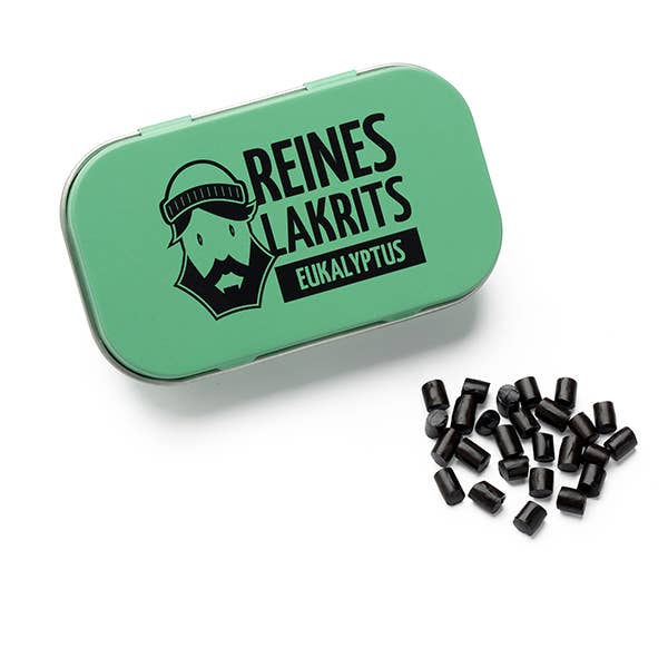 Eine grüne LASSE LAKRITS-Dose mit der Aufschrift "Dose Reines Lakrits Eukalyptus" mit einem bärtigen Gesicht steht neben zuckerfreien Lakritz-Bonbons auf weißem Hintergrund.