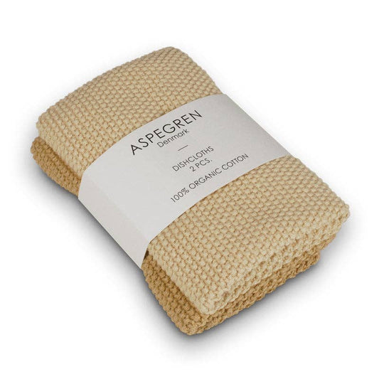 Zwei gefaltete, goldfarbene, gestrickte Geschirrtücher aus 100% Bio-Baumwolle, eingewickelt in ein weißes Papierband mit der Aufschrift Aspegren Denmark, Spültücher, Gestrickt, Einfarbig, 2 Stück.