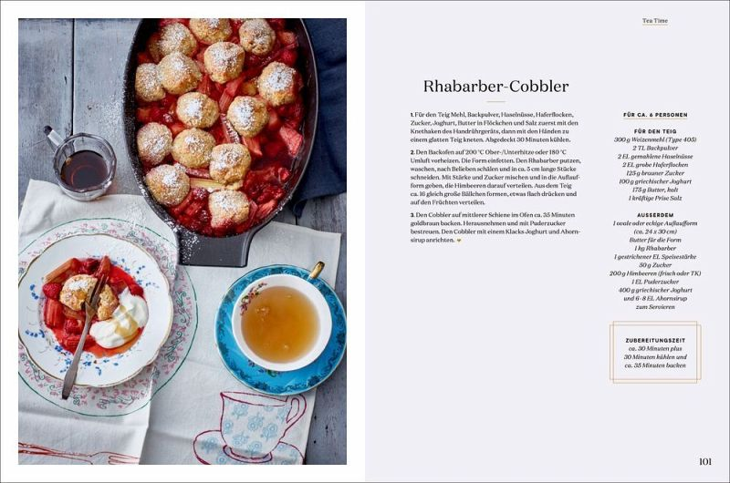 Eine Pfanne mit gebackenem Rhabarber Cobbler, einem britischen Klassiker, steht neben einem Teller mit Cobbler und Tee. Das Rezept aus "London Lovestory" vom Hölker Verlag ist auf der gegenüberliegenden Seite auf Deutsch abgebildet.