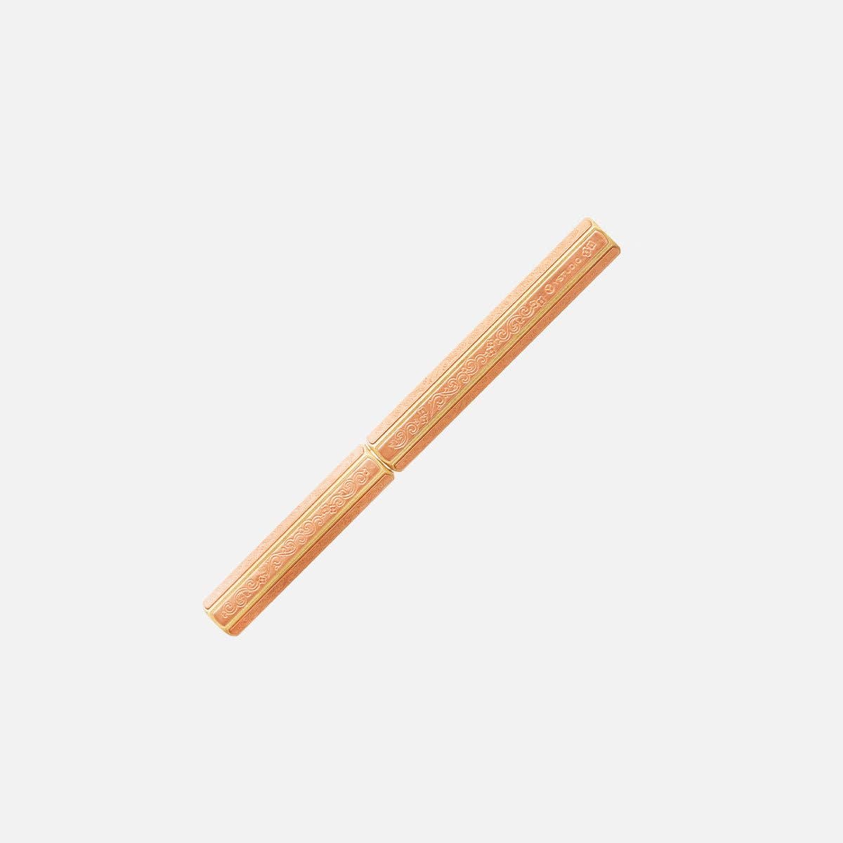 Der ENTREPÔT YSTUDIO Klassische Renaissance KAZARI KANAGU ORCHID Tintenroller, ein pfirsichfarbener Tintenroller mit goldenen Blumenmustern, die von Kazari Kanagu inspiriert sind, steht diagonal auf weißem Grund.