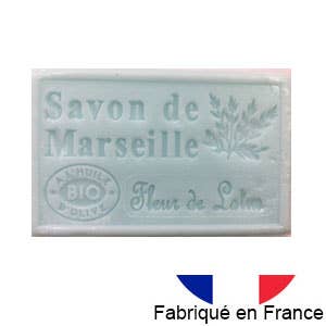 Eine hellblaue Dampa 1975 - Marseiller Seife mit Bio-Olivenöl-Lotusduft, beschriftet mit Savon de Marseille, mit einer Pflanzenabbildung, Fleur de Lotus Duft und einer kleinen französischen Flagge mit der Aufschrift Fabriqué en France.