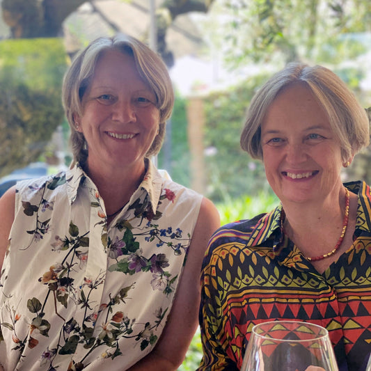 Zwei lächelnde Frauen genießen den üppigen Garten der Königlichen Gartenakademie, in dem die kreative Gestaltung im Vordergrund steht. Nehmen Sie teil an der "DREI-TAGES-MASTERCLASS - Gestalten Sie Ihren eigenen Garten" mit Gabriella Pape & Dr. Isabelle Van Groeningen, 15.-17.10.2025!.