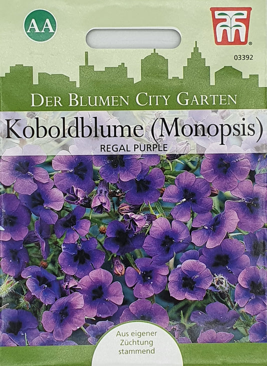 Eine Thompson und Morgan Samenpackung mit der Aufschrift Koboldblume (Monopsis) Regal Purple zeigt Büschel von kleinen, mitternachtsblauen Blüten mit einer grünen Stadtsilhouette und deutschem Text. Ideal für städtische Gärten, Hängekörbe; Einjährige.